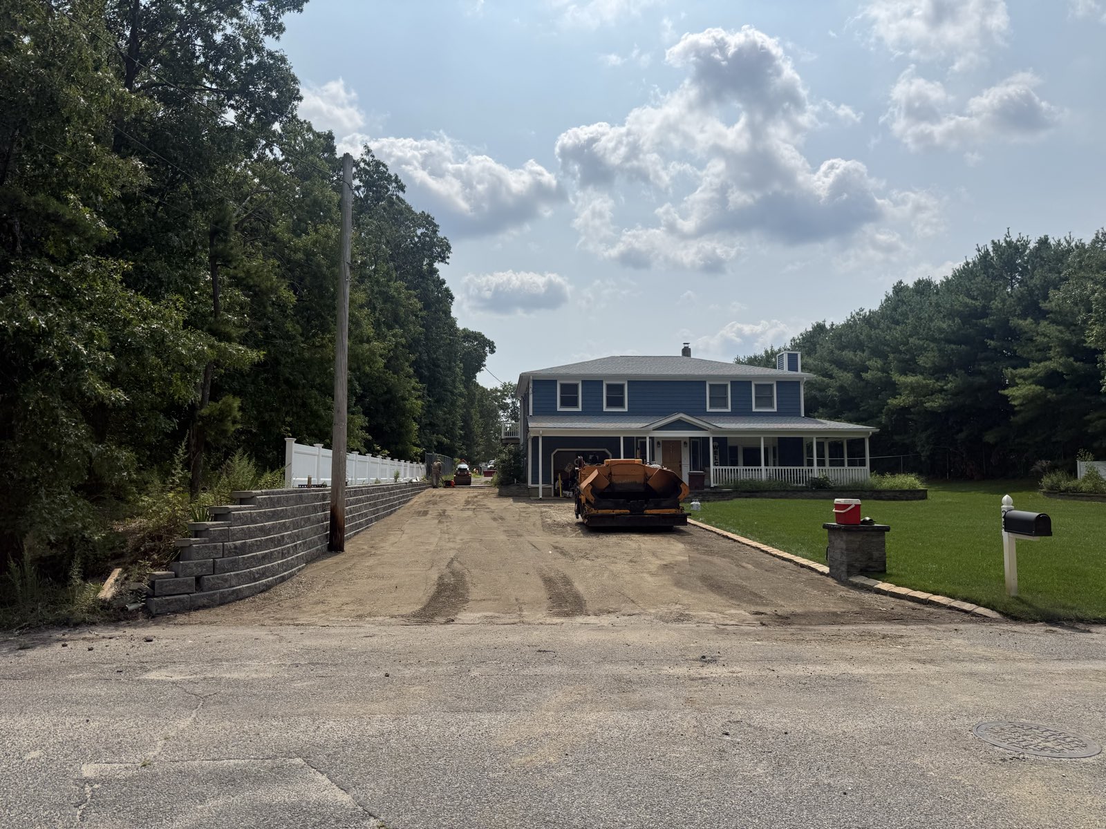 Driveway graded and base prepped, paver and roller staged for pave day