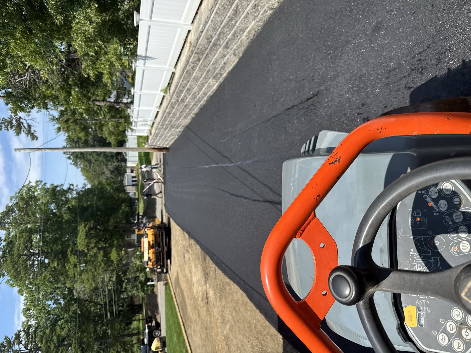 Fresh asphalt surface course going down behind the paver on a residential driveway