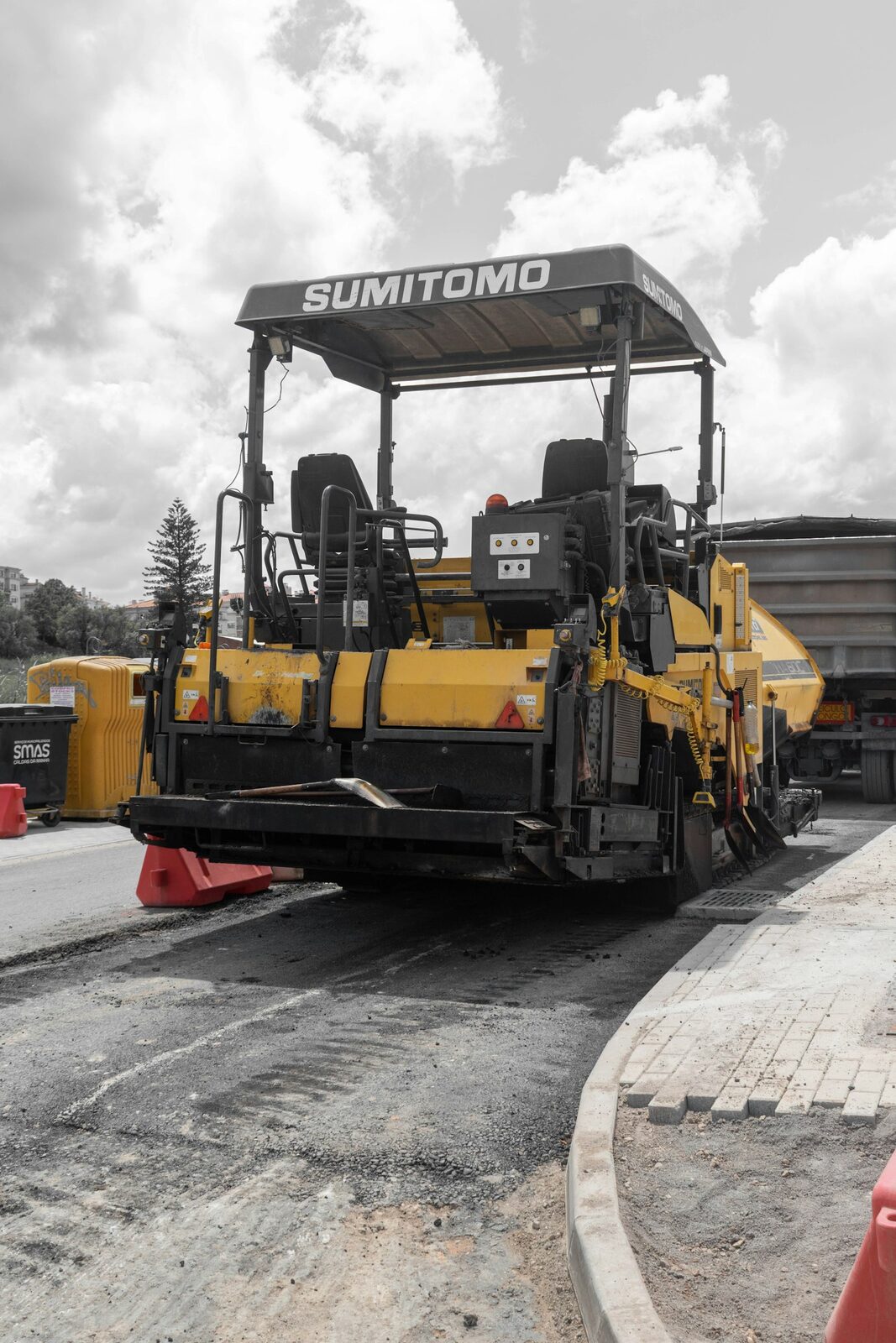 Asphalt paver laying a new surface course next to a finished curb
