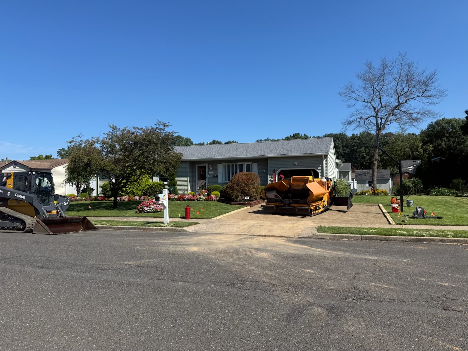 Asphalt paver loaded and set on a prepped residential driveway